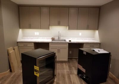 A modern kitchen featuring a refrigerator and a sink with lighting and multiple outlets