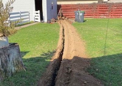 A freshly cut trench in a backyard used to bury electrical cables